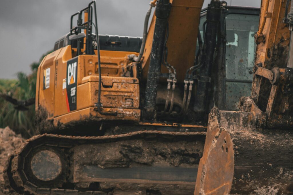 Tracked excavator on a work site awaiting repair