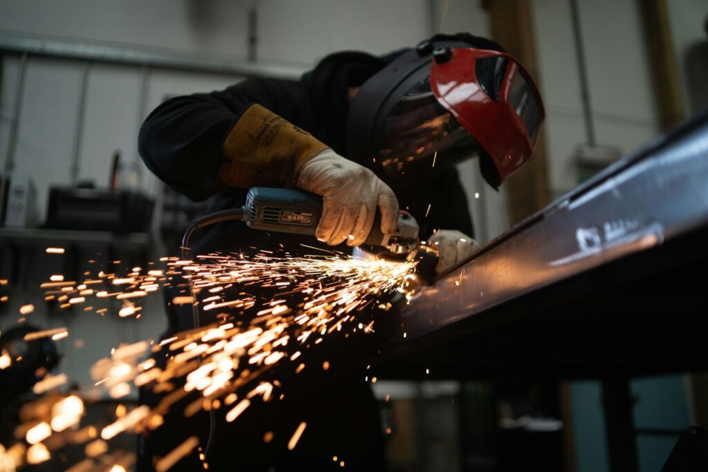 Grinder throwing sparks while shaping steel in a fabrication shop