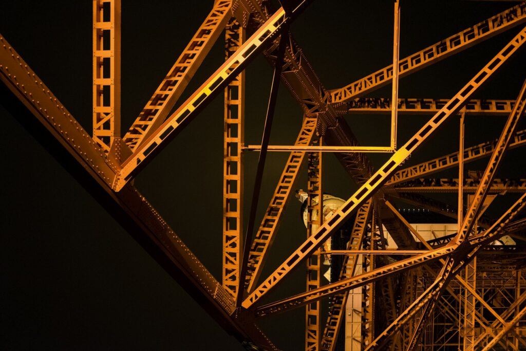 Structural steel framework lit warm against a dark sky